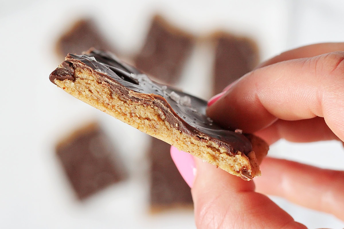 A woman's hand holding a piece of high protein cookie dough bark.