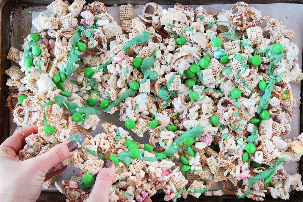 Two hands breaking pieces of leprechaun bait onto a baking sheet.