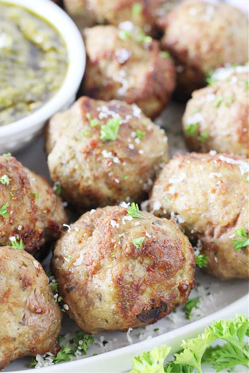 Air fryer turkey pesto meatballs topped with chopped parsley and shredded parmesan.