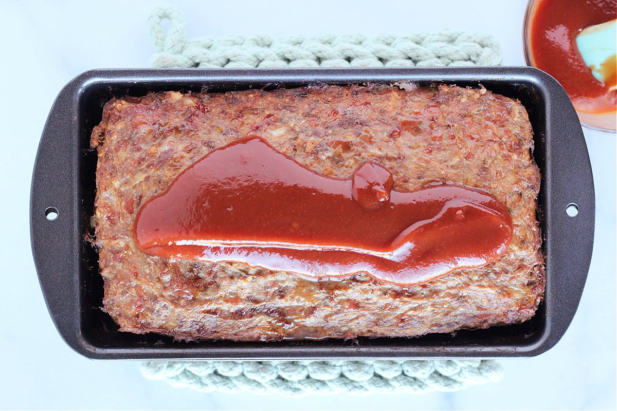 Baked meatloaf in the pan topped with ketchup sauce.