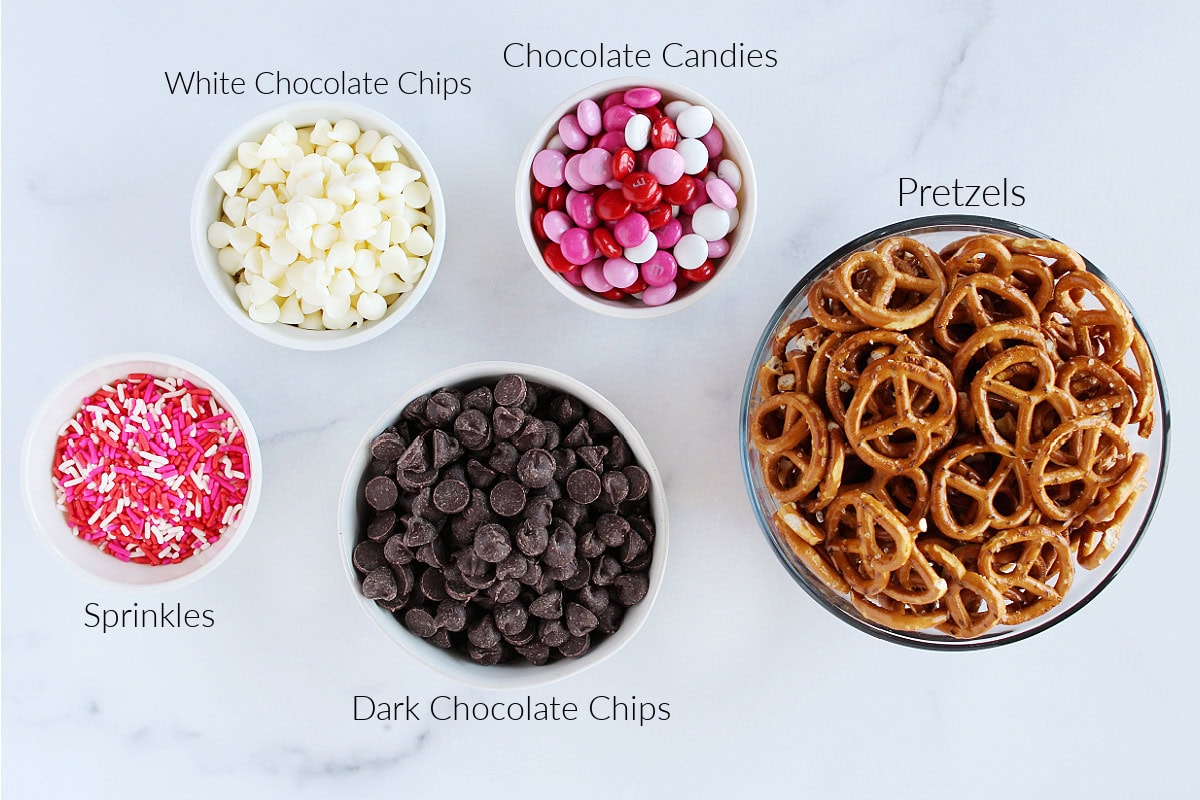 Labeled ingredients for Valentine's Day Chocolate Pretzel Bark on a white marble countertop.