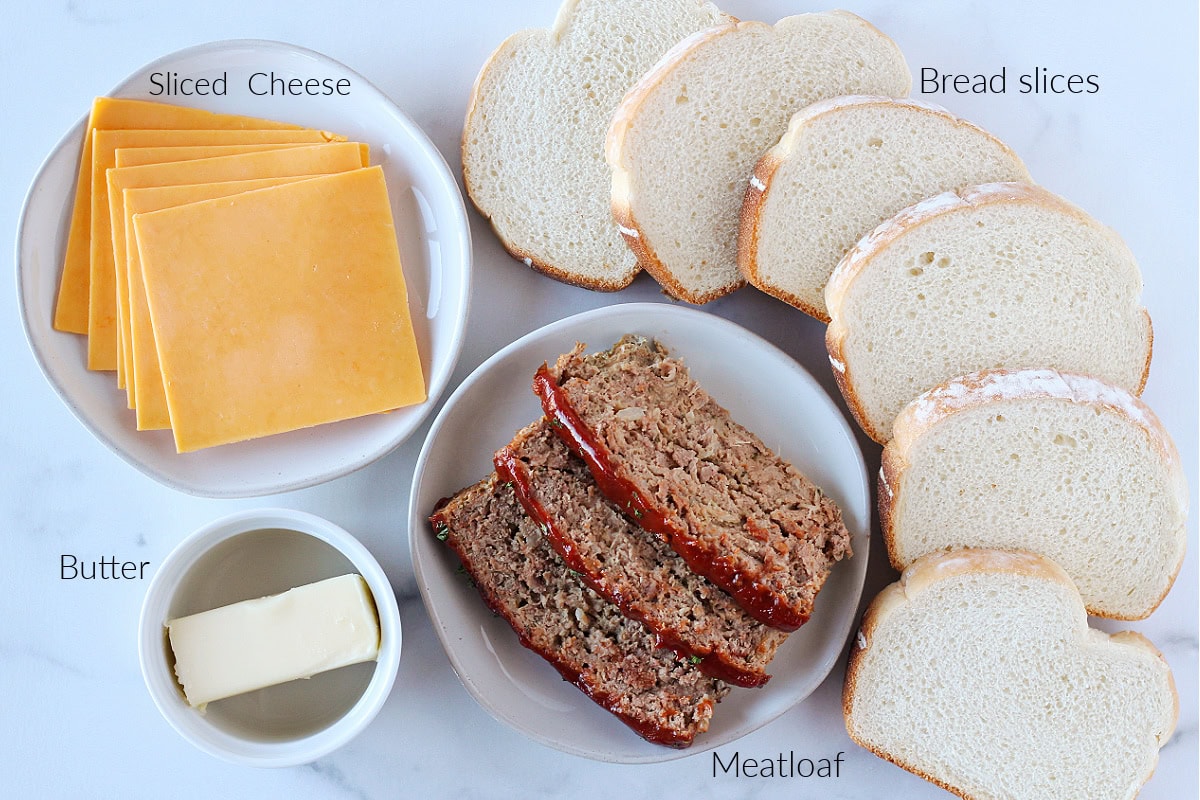 Ingredients for grilled cheese burger sandwiches on a white marble countertop.