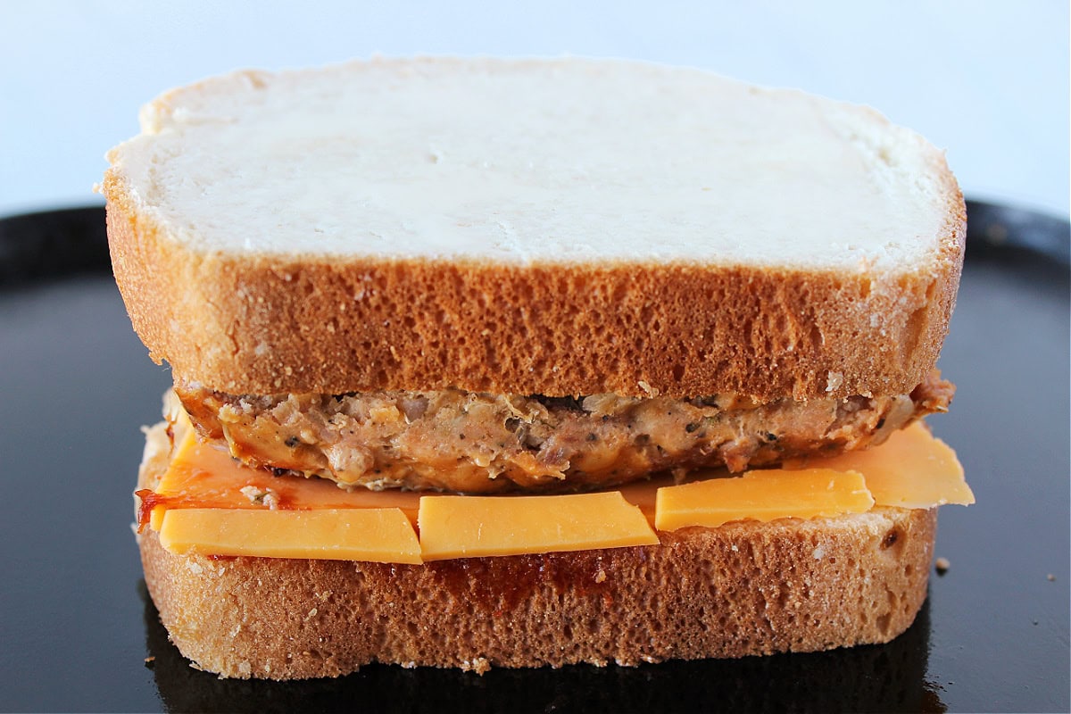 Two slices of buttered bread with sliced cheese and meatloaf in between.