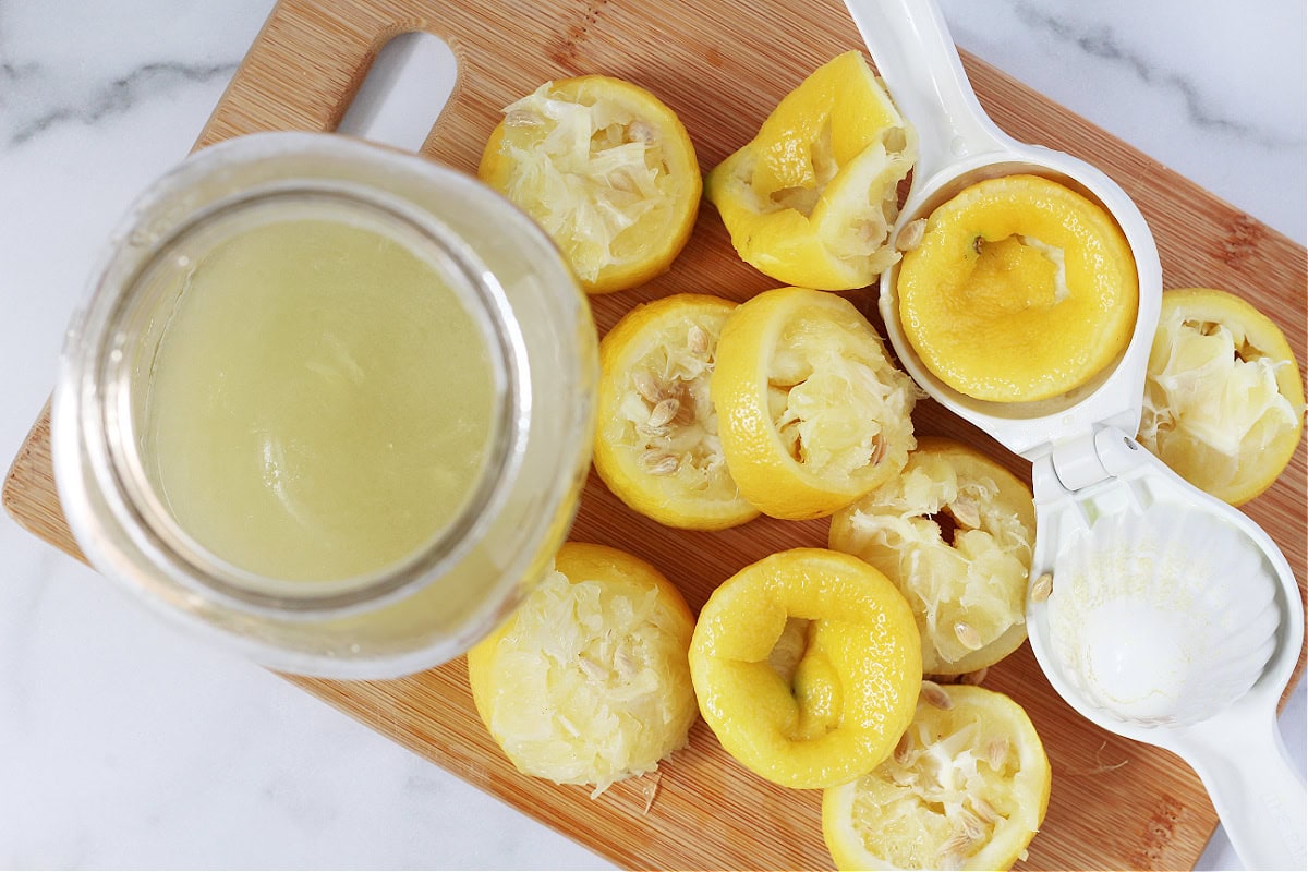Lemons squeezed with a citrus squeezer on a cutting board and lemon juice in a jar.