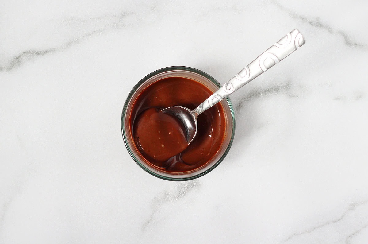 Melted chocolate in a small glass bowl with a spoon.