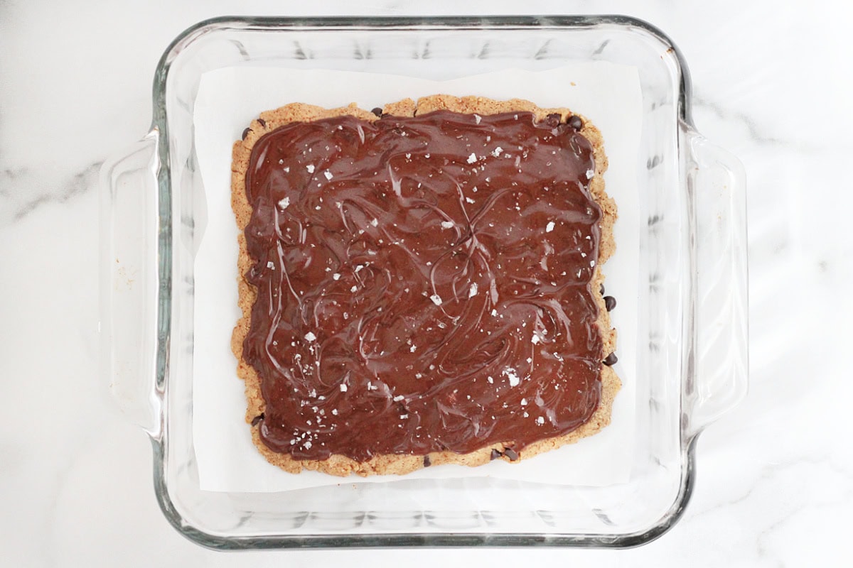 Melted chocolate spread over high protein cookie dough bark sprinkled with flaked sea salt.