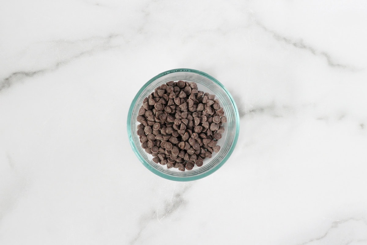 Mini chocolate chips in a small clear glass bowl.
