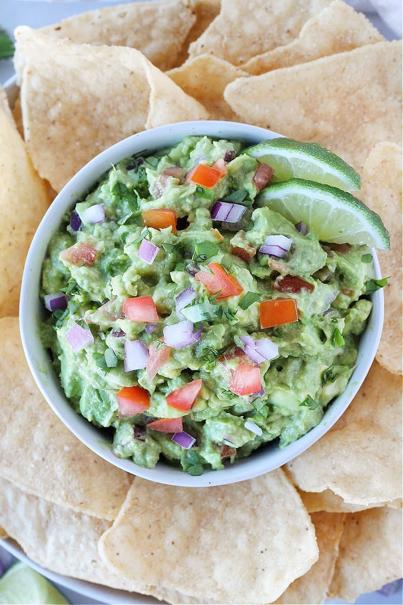 Homemade guacamole in a bowl surrounded by tortilla chips.