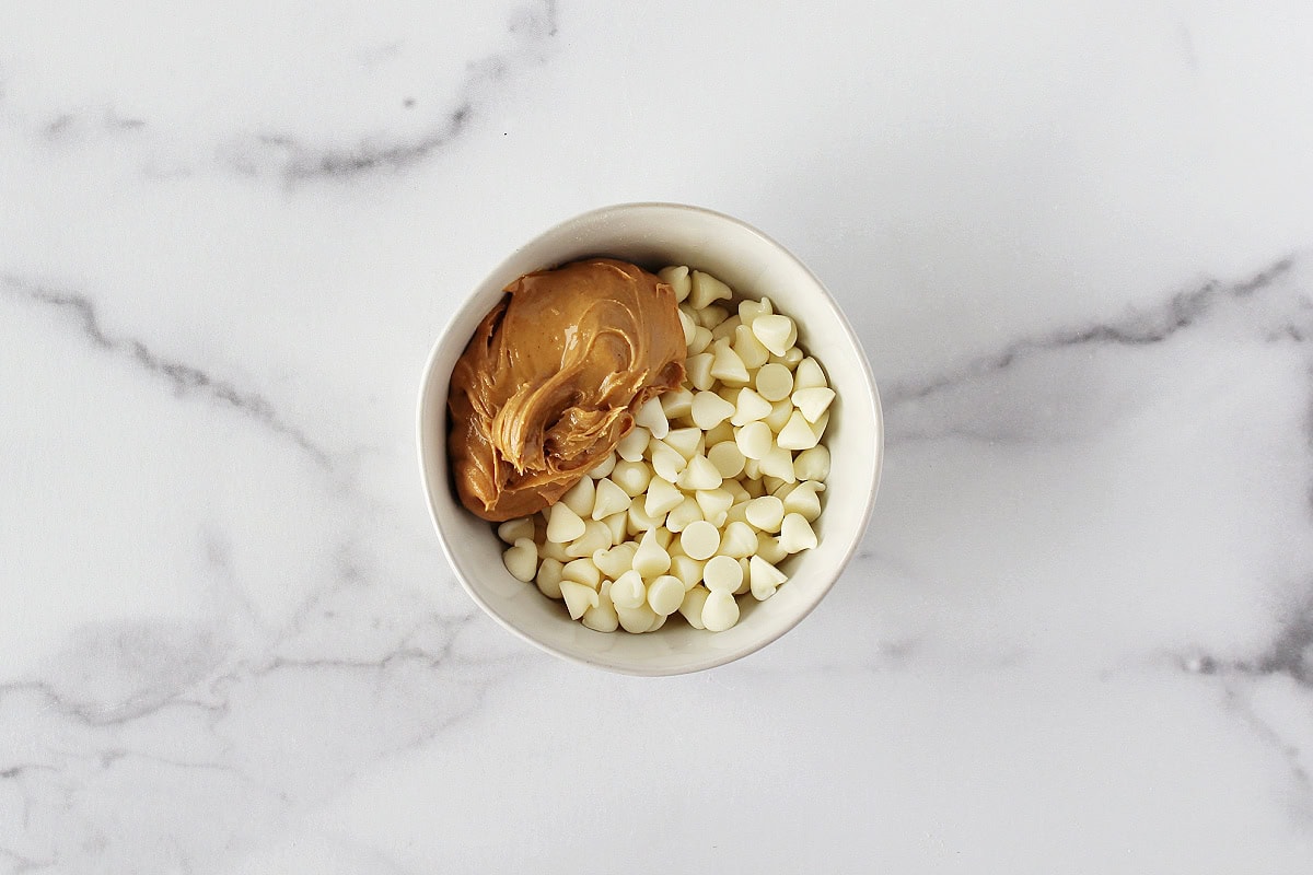 White chocolate chips and peanut butter in a small white bowl.