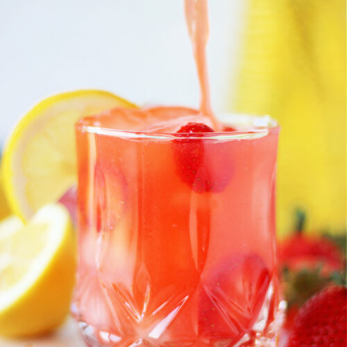 Filling a glass with homemade strawberry lemonade.