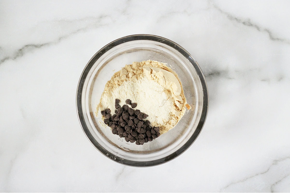 A bowl with vanilla protein powder, coconut flour, and chocolate chips.