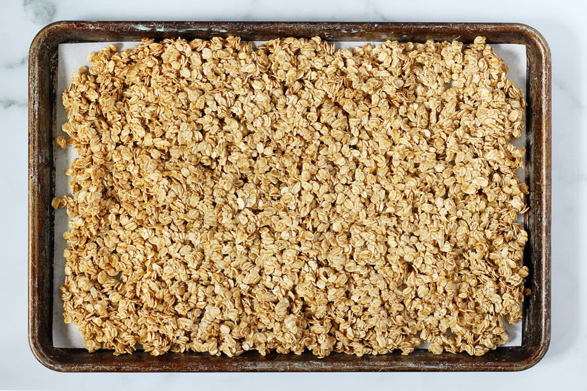 Unbaked French toast granola on parchment paper on a metal sheet pan.