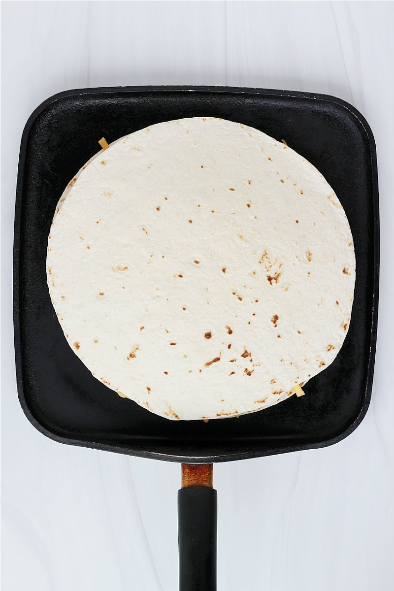 A sloppy joe quesadilla on a flat black stovetop pan.