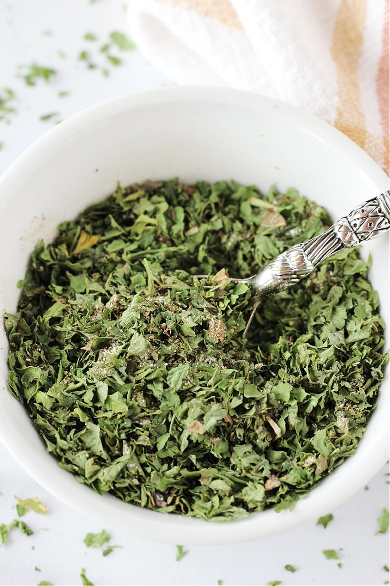Dried parsley, dried basil, and other seasonings in a bowl.
