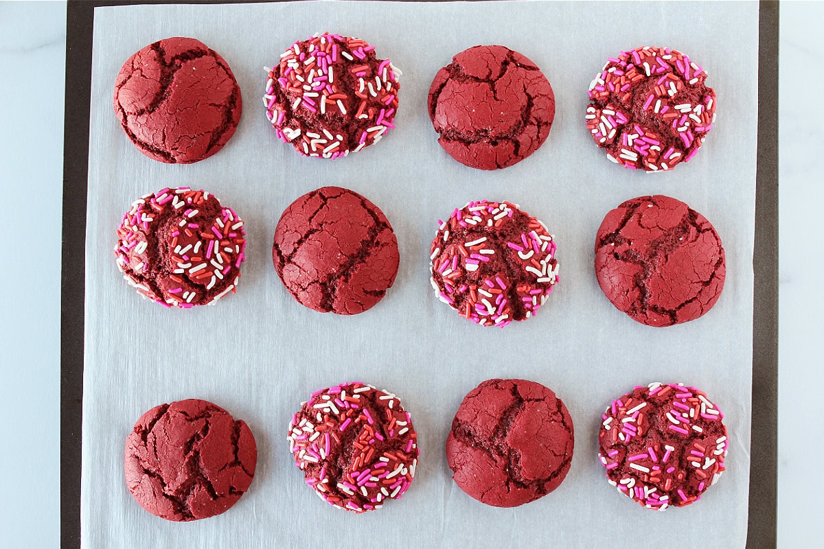 Twelve baked red velvet cookies on a baking sheet.