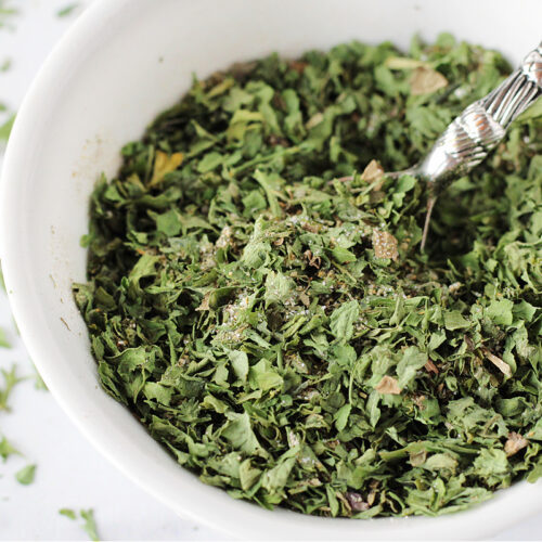 A spoon in a bowl of homemade low sodium ranch seasoning mix.