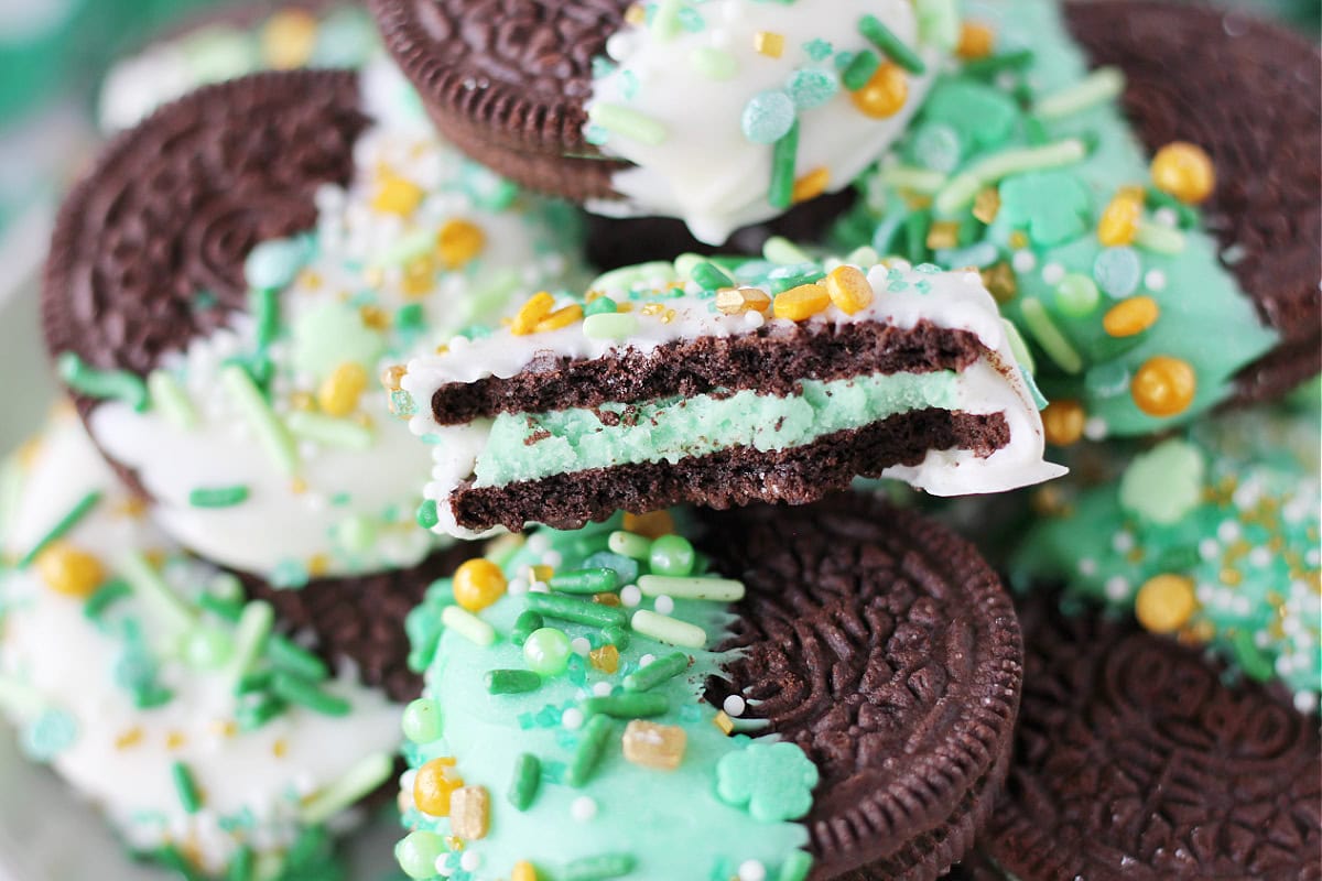 A bite taken out of a dipped Oreo with St. Patrick's Day sprinkles.