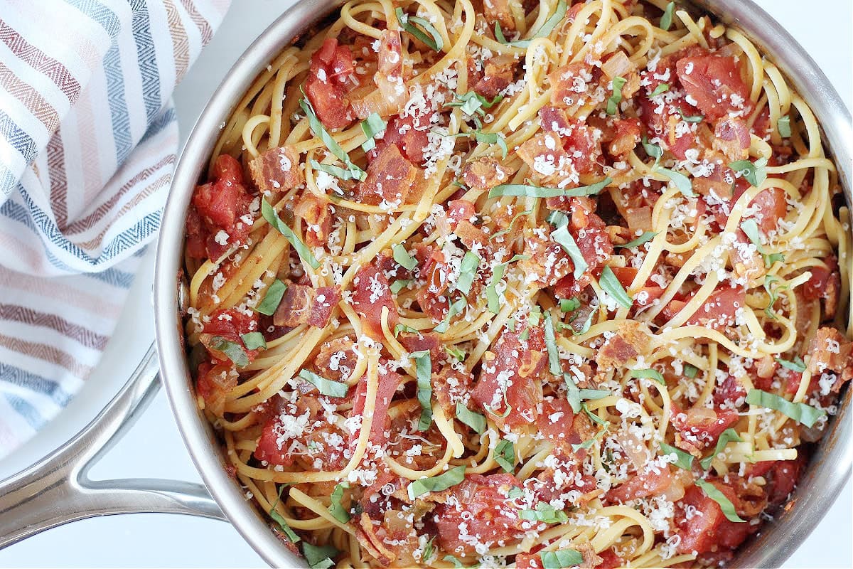 A large sauté pan with linguine pasta and stewed tomatoes recipe.