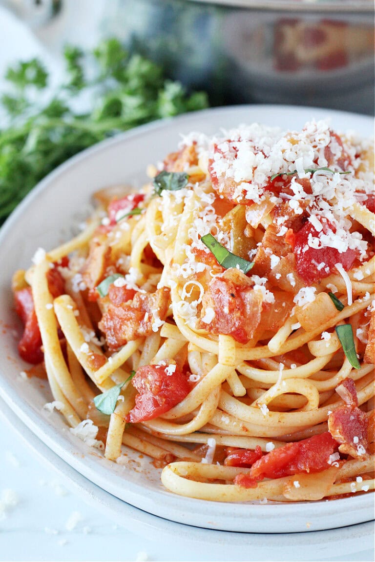 Homemade Pasta All’Amatriciana on a white plate topped with cheese.