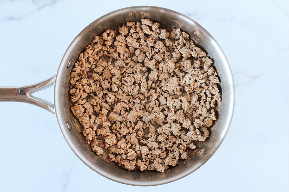 Browned ground meat in a stainless sauté pan.