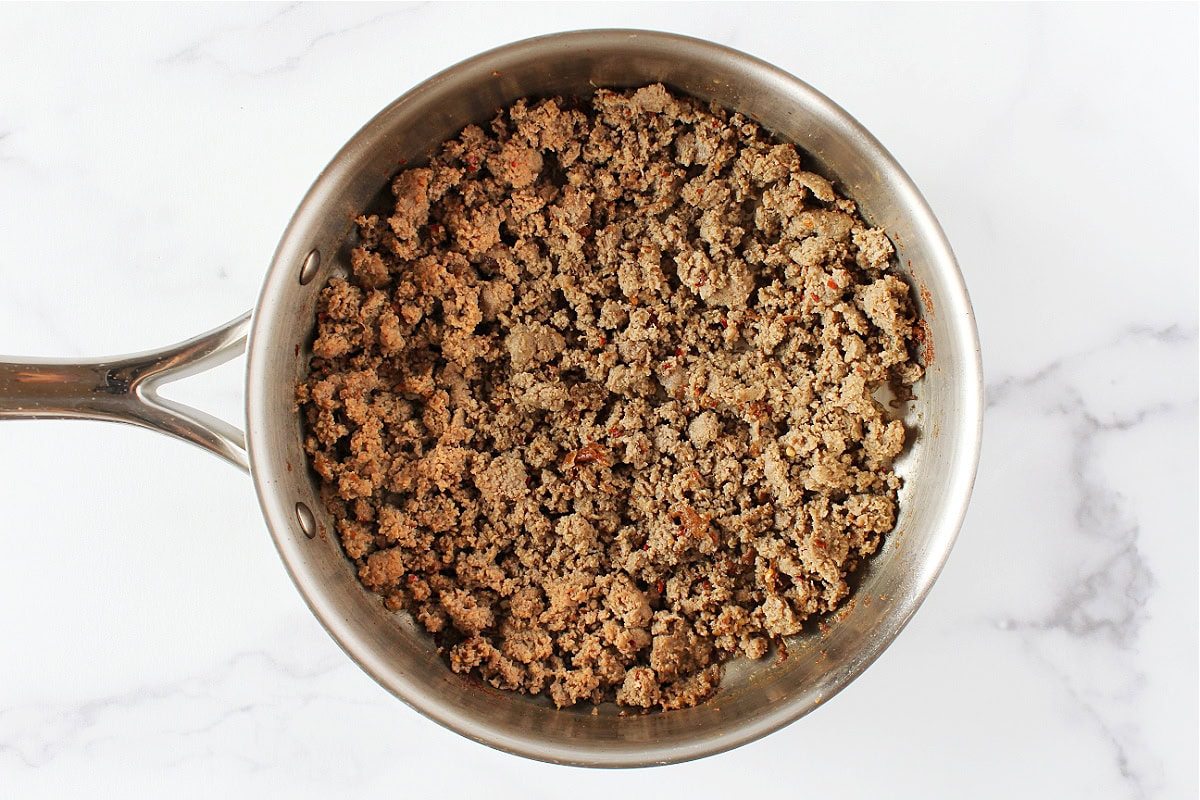 Browned ground turkey sausage in a stainless steel sauté pan.