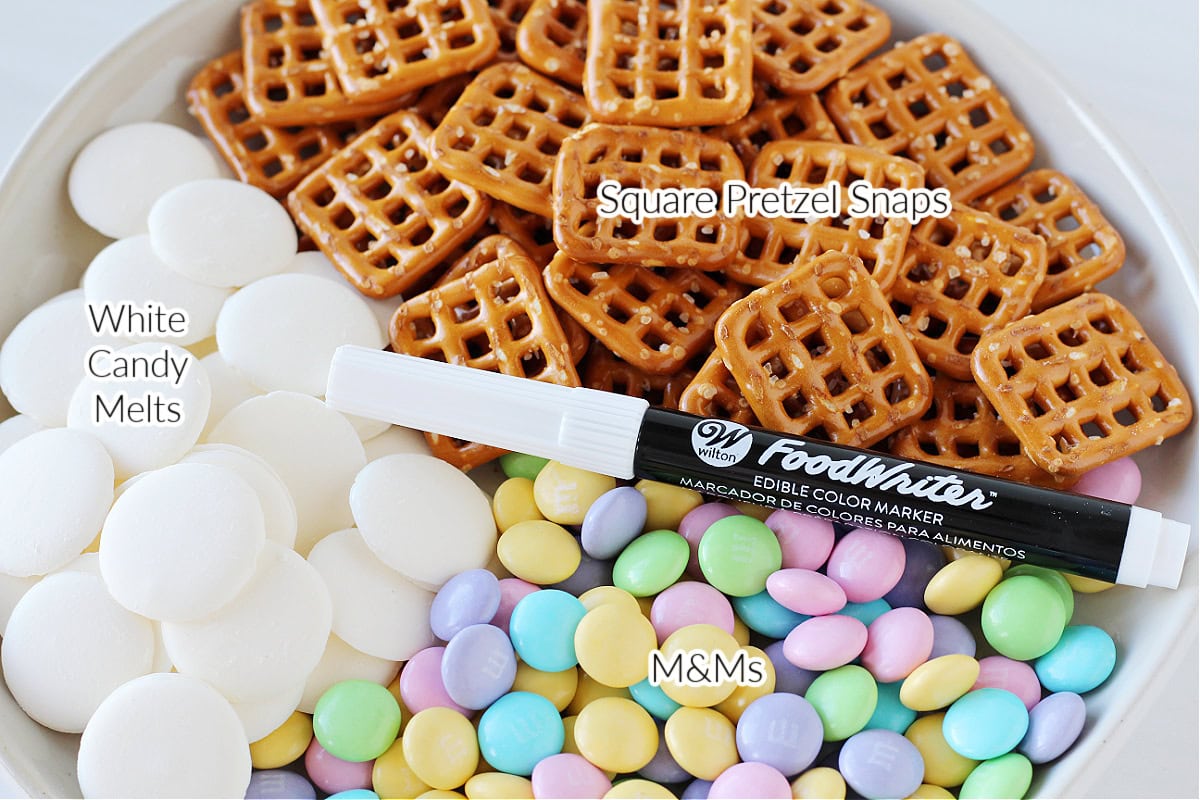 Labeled ingredients for bunny pretzel treats on a white plate.
