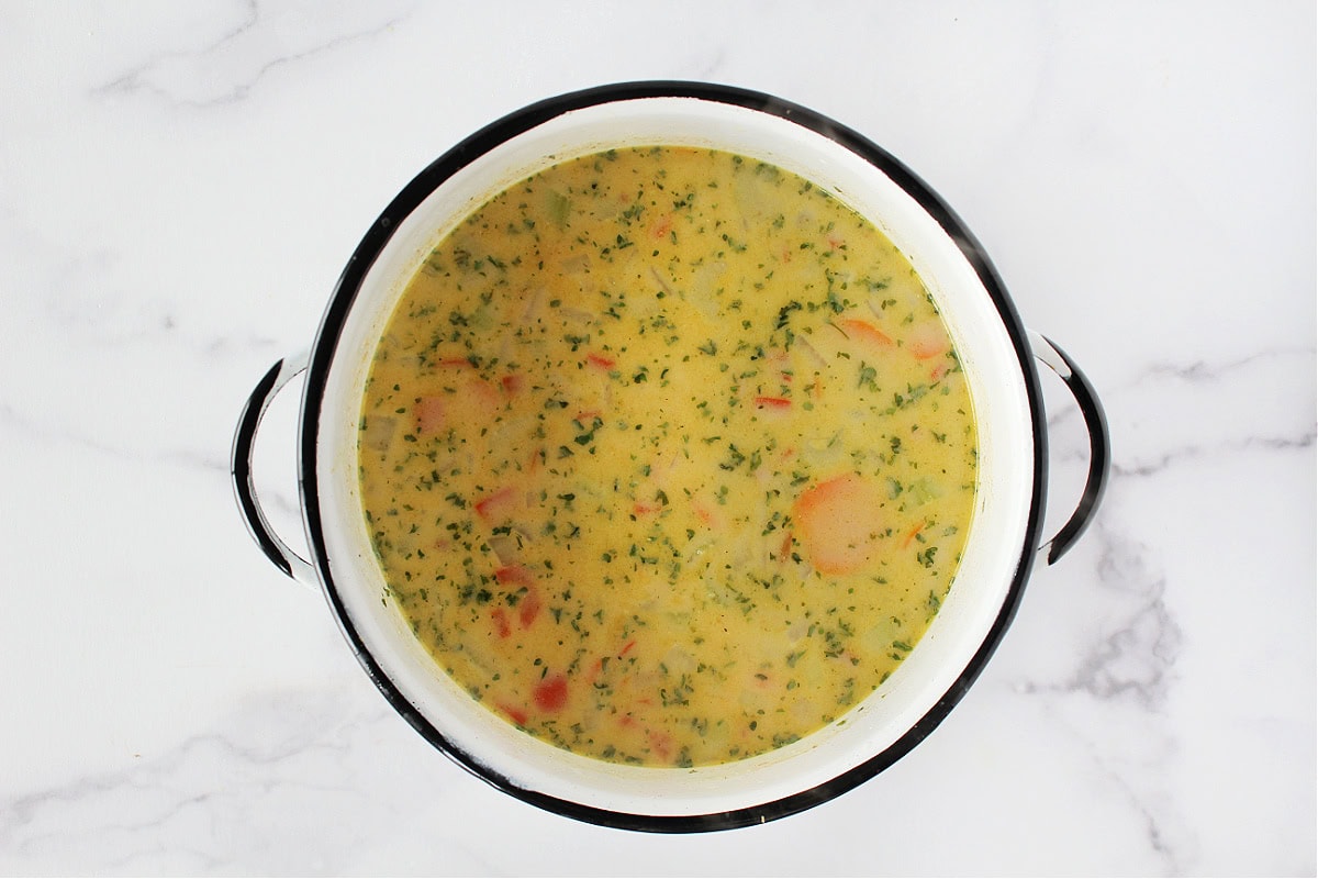 Creamy cheeseburger soup in a white soup pot.