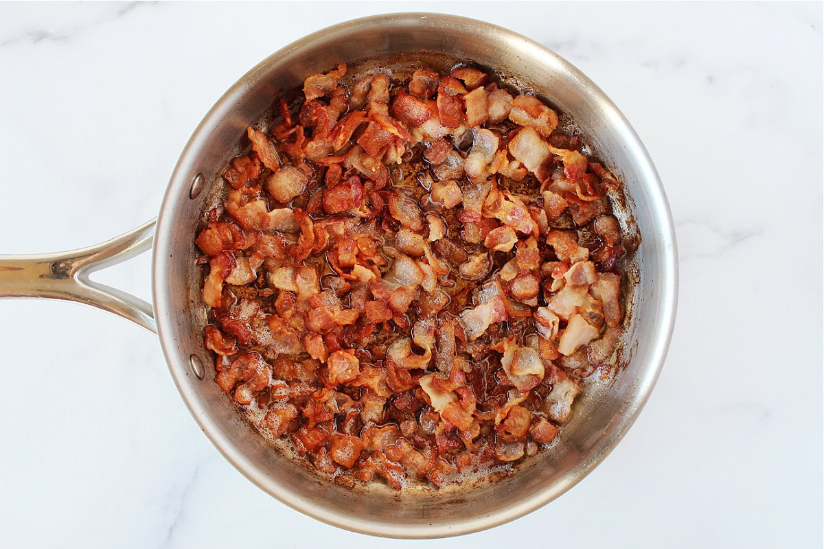 Chopped bacon cooked in a sauté pan.