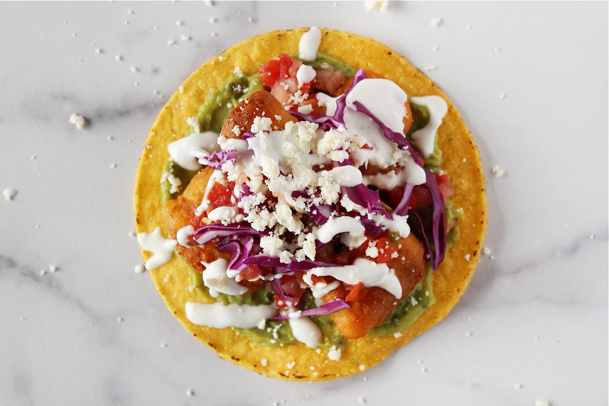 Lime crema drizzled over battered fish filets and pico de gallo tostadas.