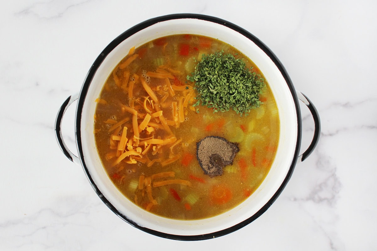 Shredded cheese, parsley and black pepper sitting atop a soup.