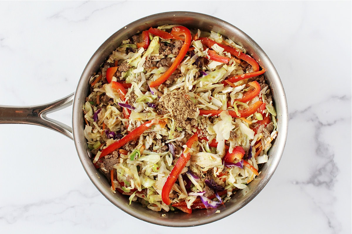 Sliced red pepper, ground ginger, sauteed coleslaw and browned ground turkey in pan.