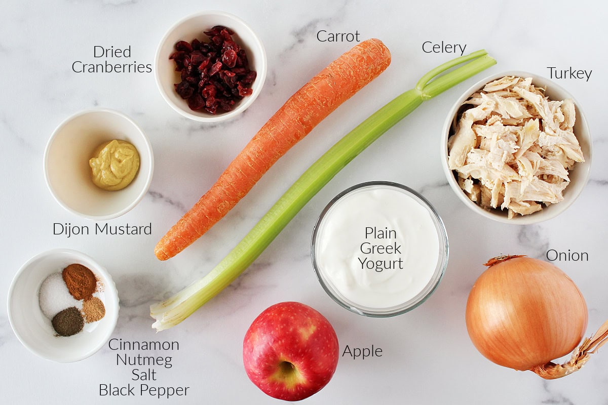 Labeled ingredients for leftover turkey salad on a white marble countertop.