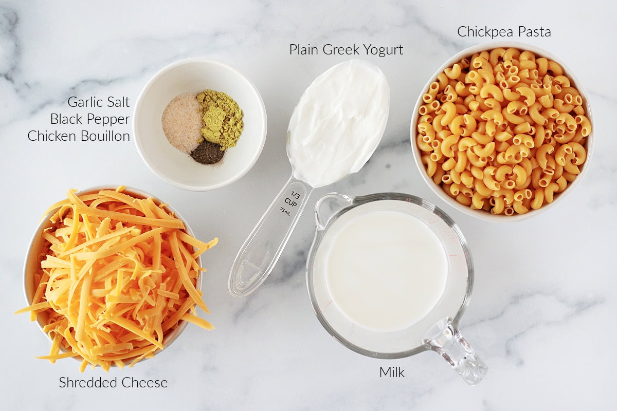 Labeled ingredients for high protein mac and cheese on a white marble countertop.