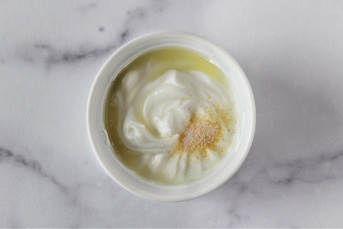 Lime juice, garlic salt and plain Greek yogurt in a white mixing bowl.