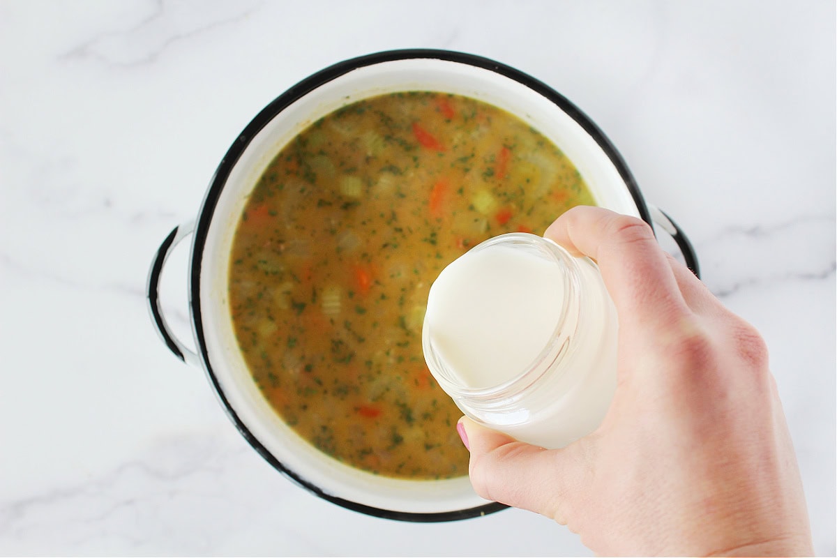 Pouring half and half into a pot of soup.