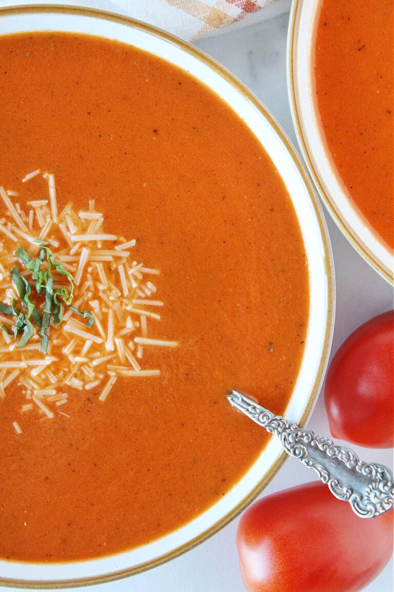 Bowl of homemade tomato soup topped with Parmesan cheese with a spoon .