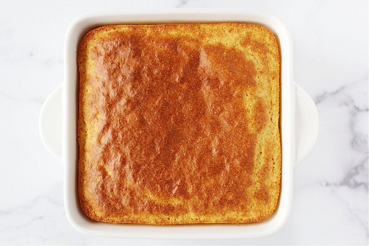 Golden brown cornbread in an 8x8 white baking dish.