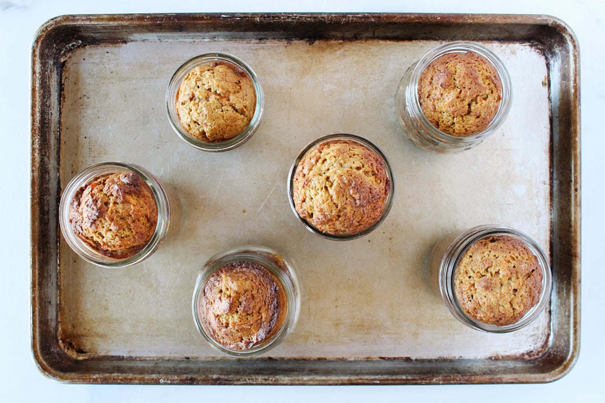 Six jars of baked single serve carrot cakes in mason jars.
