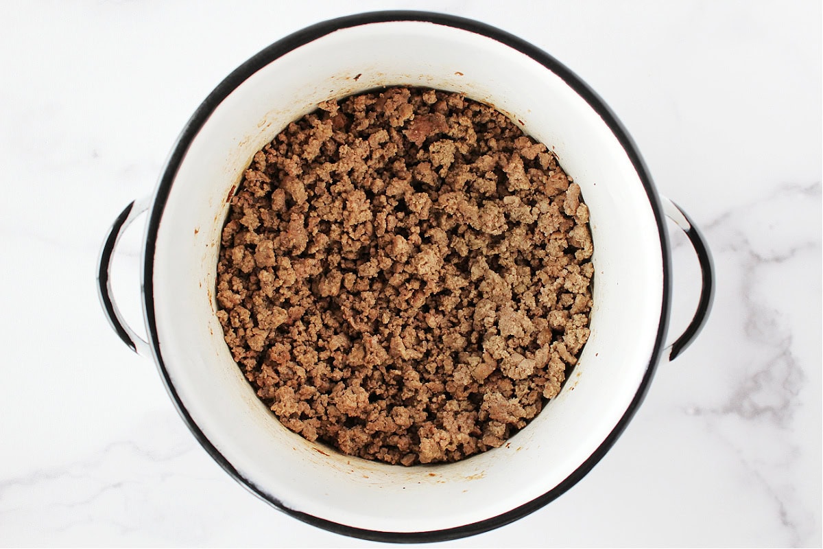 Browned ground beef in a white soup pot.