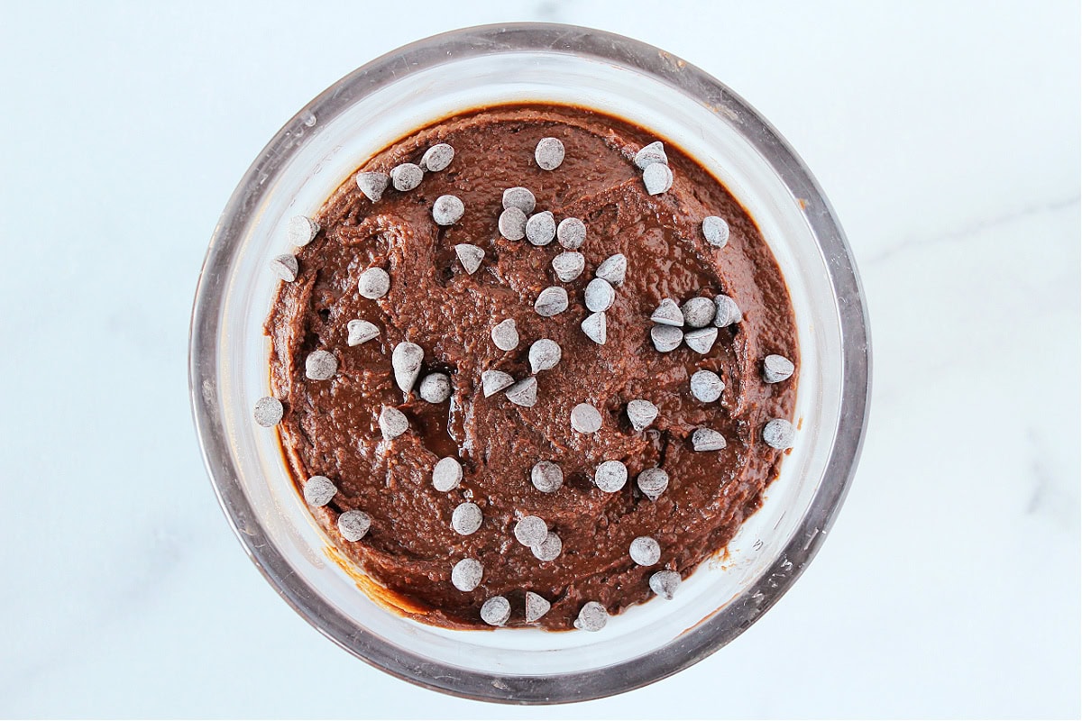 Brownie batter hummus topped with chocolate chips in a glass bowl.