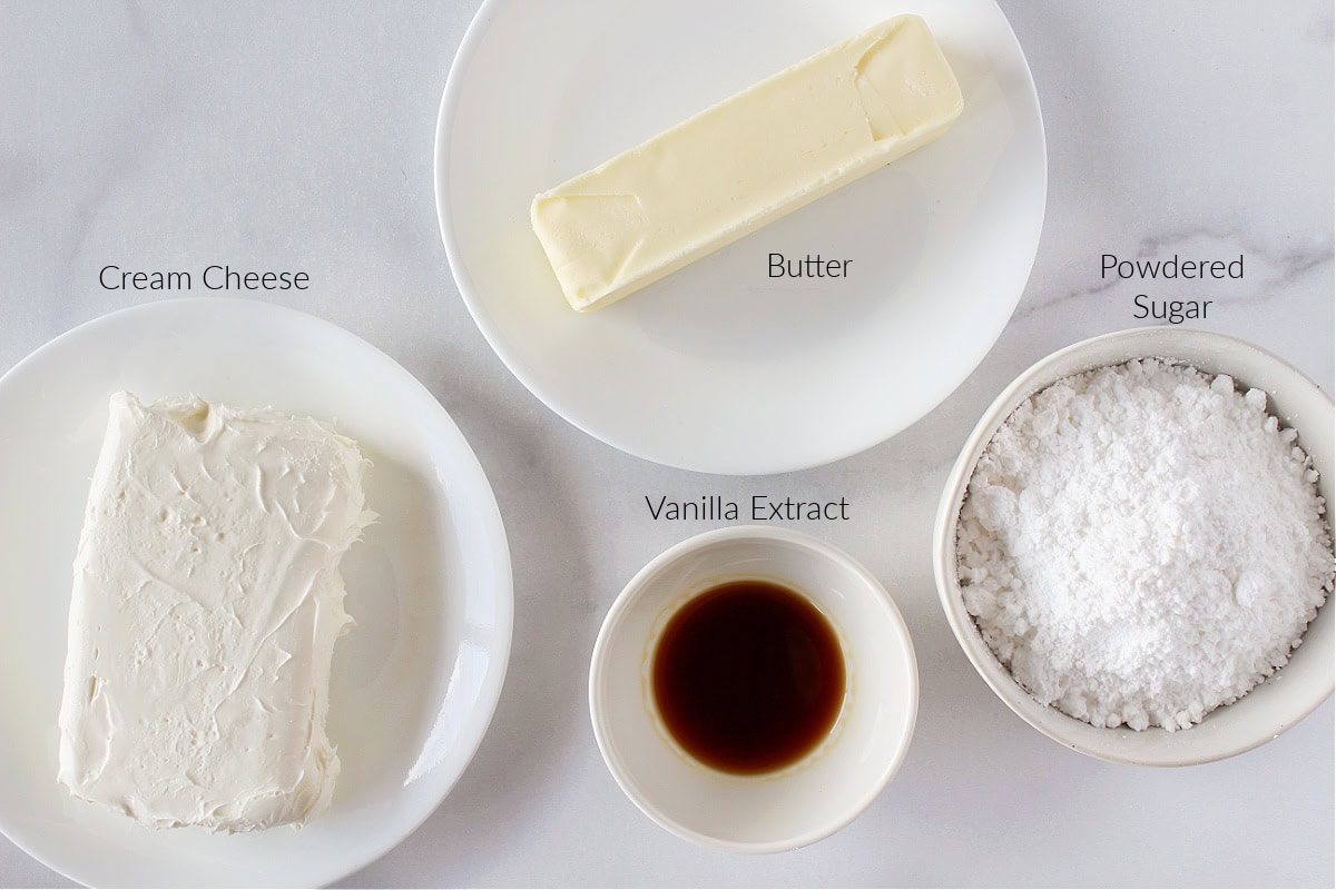 Labeled ingredients for cream cheese frosting on a white marble countertop.
