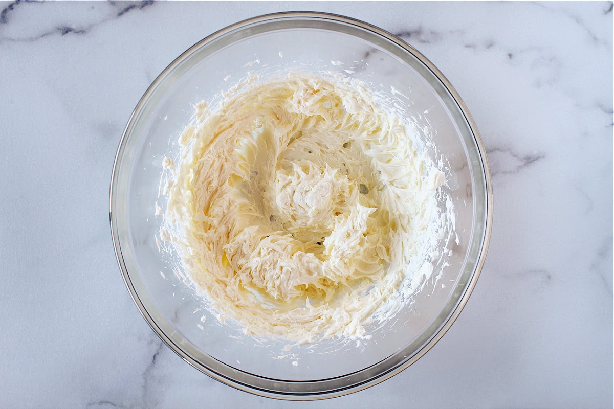 Butter and cream cheese mixed together in a glass mixing bowl.