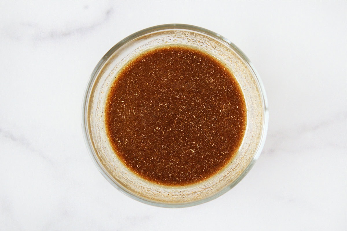 Cumin and seasonings mixed with lime juice in a glass bowl.
