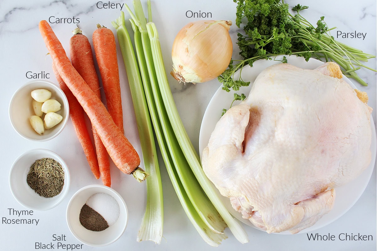 Labeled ingredients on a white marble countertop for boiling a whole chicken.