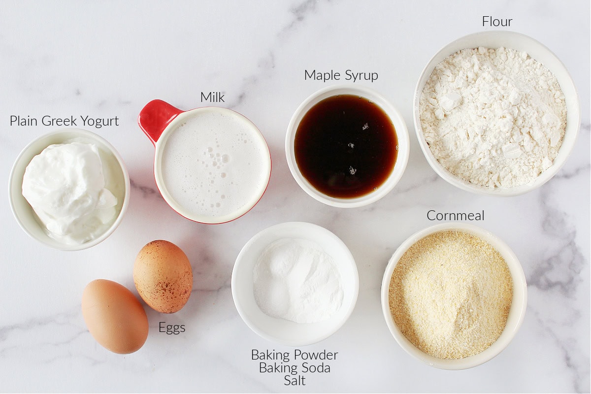 Labeled ingredients for healthy maple cornbread on a white marble countertop.