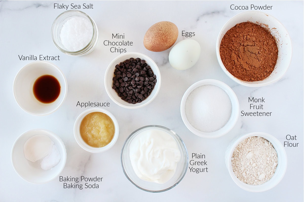 Labeled ingredients on a white marble countertop for low calorie brownies with Greek yogurt.
