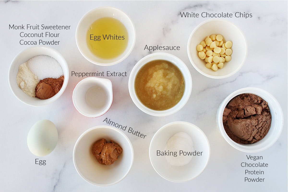 Labeled ingredients for a peppermint chocolate cake with protein on a white marble countertop.