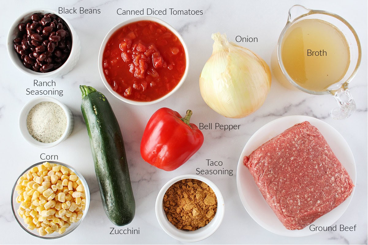 Labeled ingredients for taco soup on a white marble countertop.