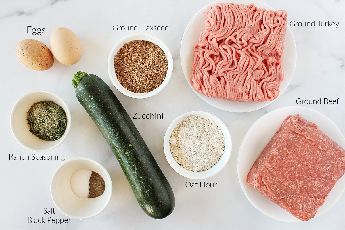 Labeled ingredients for whole foods meatloaf with zucchini on a white marble countertop.