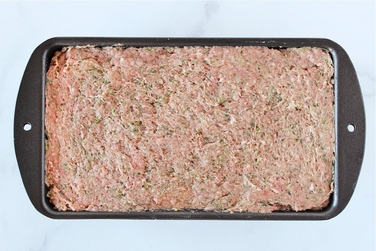 Raw meatloaf mixture pressed into a 9x5 metal pan.